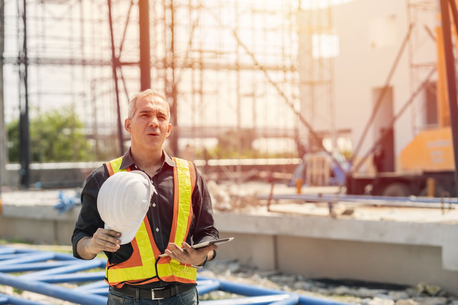 construction worker wearing hi vis vest on the construction site working under the heat of the sun.